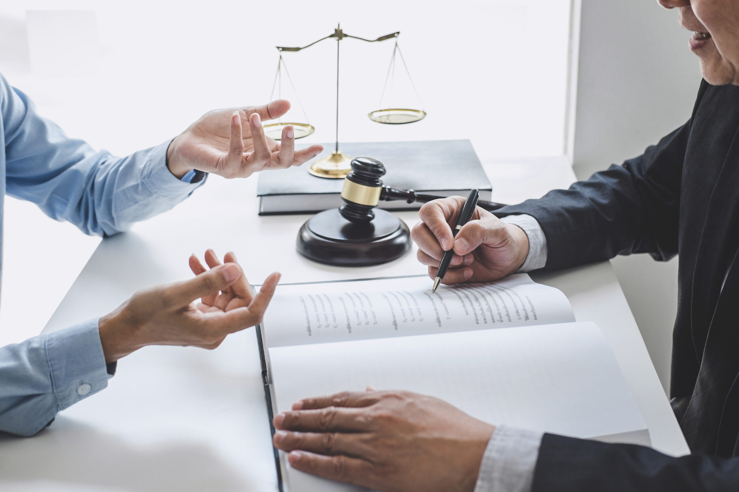 Hands signing legal documents at a wooden office desk